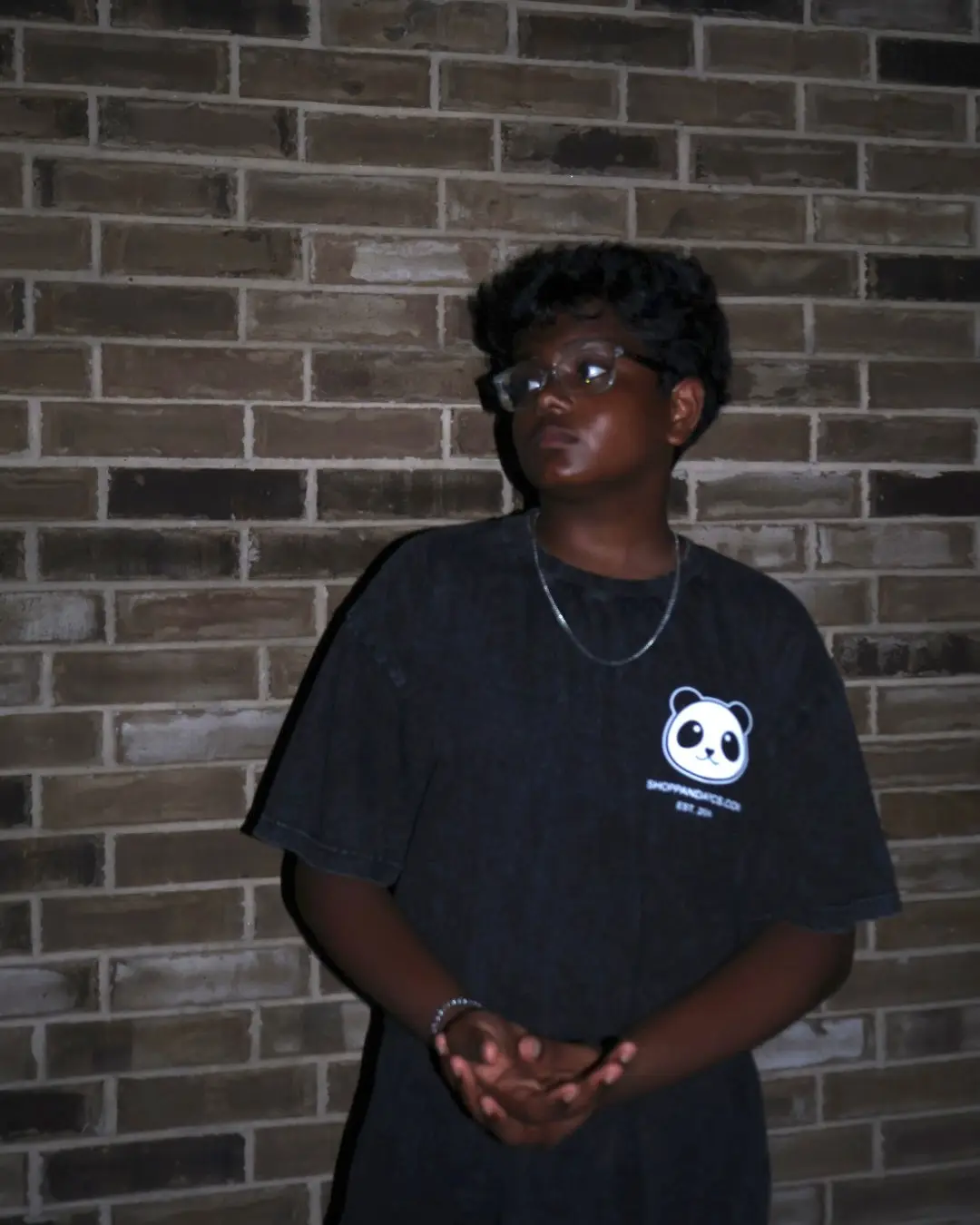 Kavin standing against a brick wall, wearing a PandaPCs T-shirt.